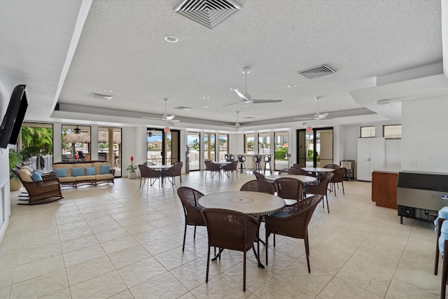 tiled dining space featuring french doors, a raised ceiling, and ceiling fan