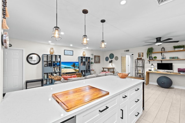 kitchen with built in desk, white cabinets, ceiling fan, and decorative light fixtures