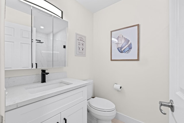 bathroom featuring a shower with shower door, vanity, and toilet