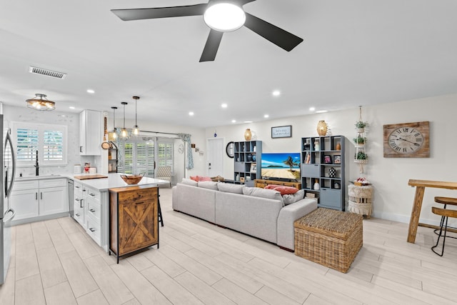 living room with ceiling fan, sink, and light hardwood / wood-style floors