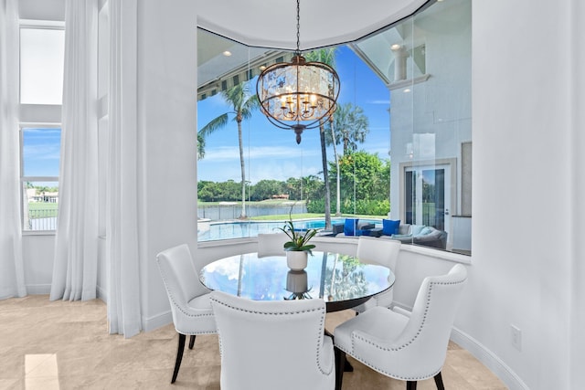 dining area with a water view, a chandelier, and a wealth of natural light