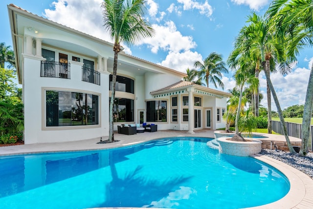 back of property with a pool with hot tub, a balcony, an outdoor living space, and a patio area