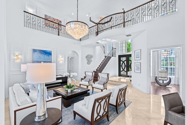 living room featuring wood-type flooring, a towering ceiling, and a notable chandelier