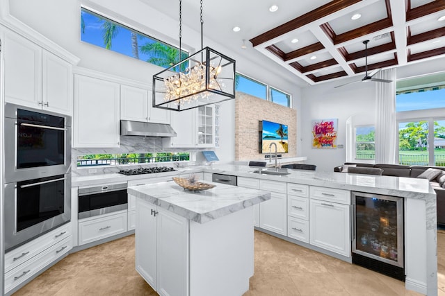 kitchen with wine cooler, kitchen peninsula, plenty of natural light, and sink