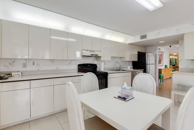 kitchen with black electric range, sink, light tile patterned floors, and white cabinets