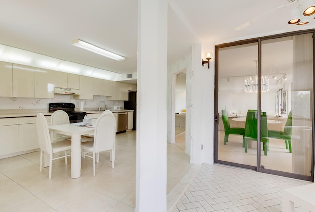 dining area with an inviting chandelier, light tile patterned floors, and sink