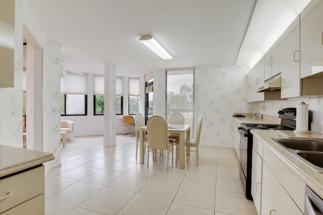 kitchen with white cabinets, light tile patterned floors, black / electric stove, and custom range hood