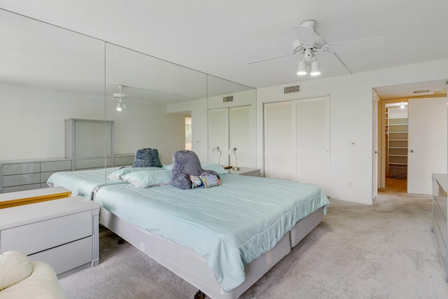 bedroom featuring ceiling fan, a textured ceiling, and light carpet