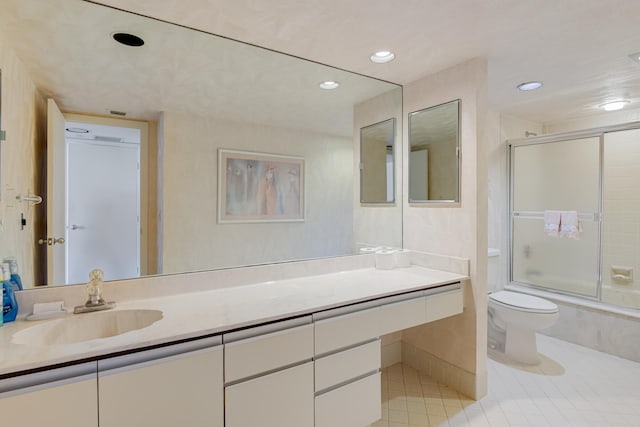 full bathroom featuring bath / shower combo with glass door, vanity, toilet, and tile patterned floors