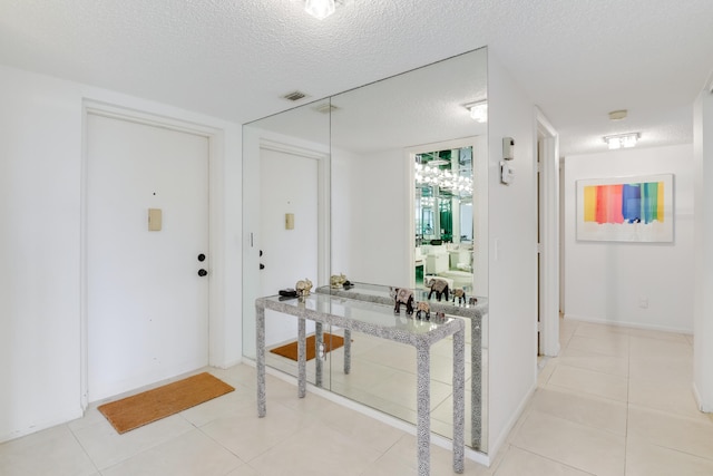 hall with a textured ceiling and light tile patterned floors