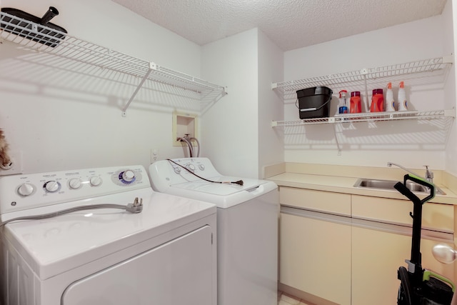 clothes washing area with a textured ceiling, sink, and washing machine and dryer