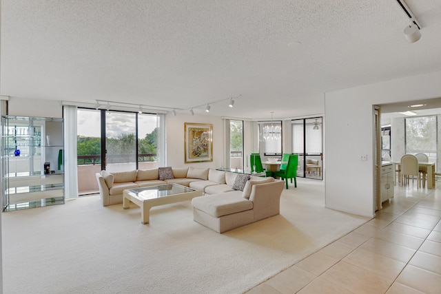 living room featuring a notable chandelier, a textured ceiling, light tile patterned flooring, and rail lighting