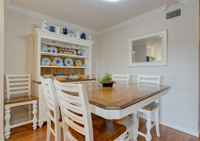 dining room with wood-type flooring and crown molding