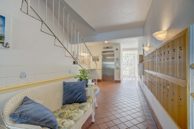 hallway with a textured ceiling, elevator, and tile patterned floors