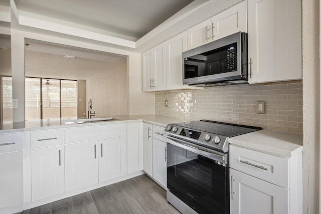 kitchen featuring decorative backsplash, white cabinets, stainless steel appliances, wood-type flooring, and sink