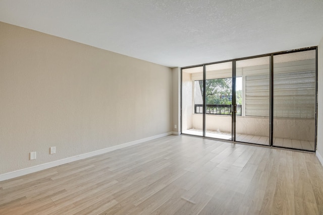 spare room with light wood-type flooring and a textured ceiling