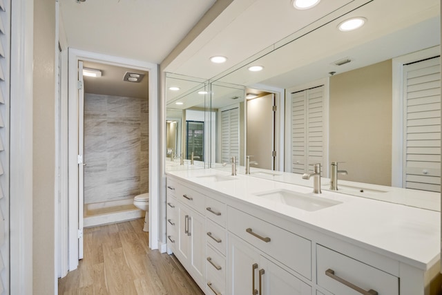 bathroom featuring vanity, a shower, hardwood / wood-style flooring, tile walls, and toilet