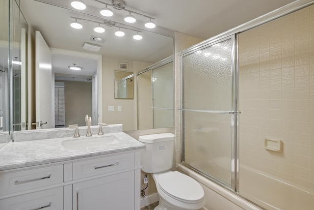 full bathroom with bath / shower combo with glass door, vanity, and toilet