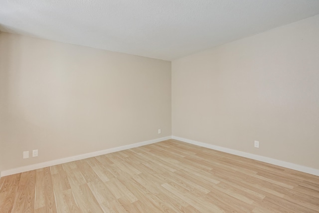 spare room featuring a textured ceiling and light hardwood / wood-style flooring