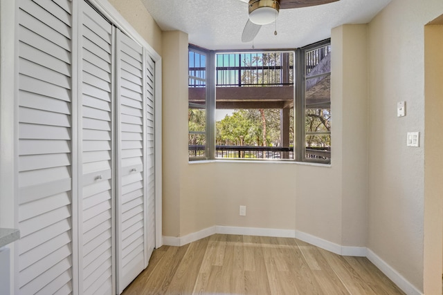 unfurnished bedroom with ceiling fan, a textured ceiling, light wood-type flooring, and a closet