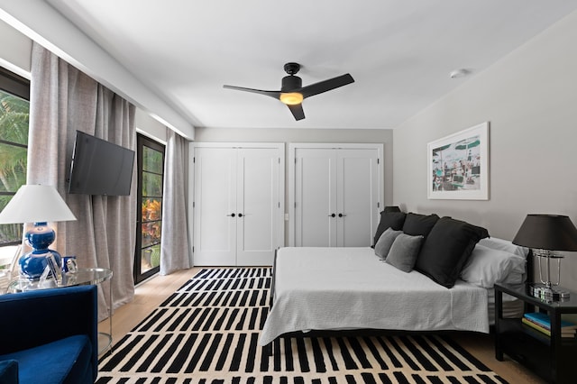 bedroom featuring multiple closets, multiple windows, hardwood / wood-style flooring, and ceiling fan