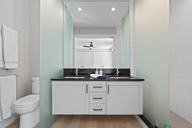 bathroom with wood-type flooring, ceiling fan, vanity, and toilet