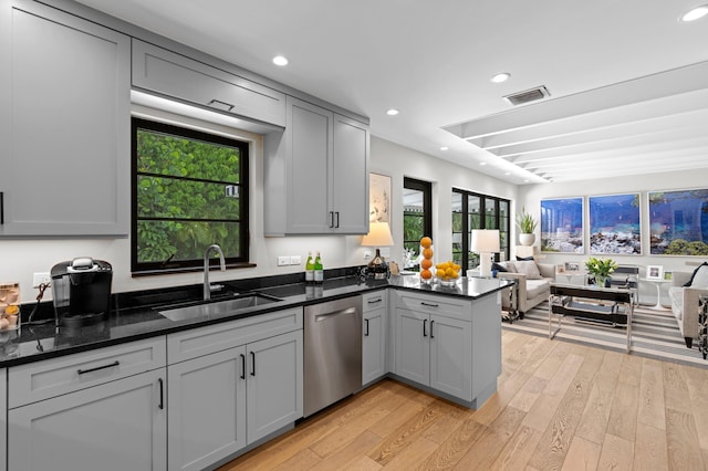 kitchen featuring sink, gray cabinetry, dishwasher, dark stone counters, and light hardwood / wood-style floors