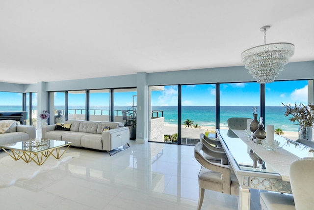 living room with a chandelier, a water view, a view of the beach, and light tile patterned flooring