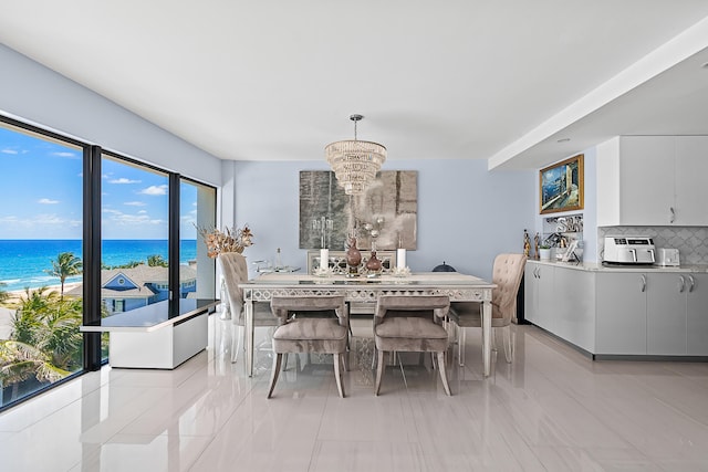 tiled dining room featuring a notable chandelier and a water view