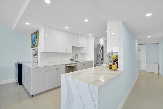 kitchen with sink, kitchen peninsula, appliances with stainless steel finishes, tasteful backsplash, and white cabinetry