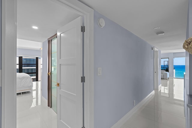 hallway with a water view and light tile patterned floors