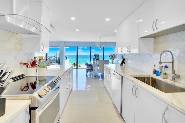 kitchen with a water view, sink, wall chimney exhaust hood, white cabinetry, and stainless steel appliances