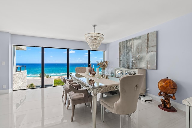 tiled dining room with a view of the beach, a water view, and a chandelier