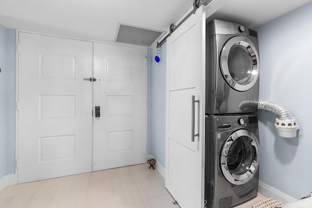 clothes washing area with stacked washing maching and dryer