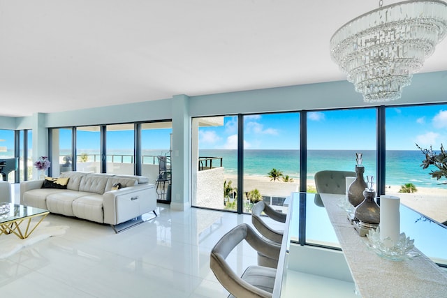 living room featuring a notable chandelier, a water view, a beach view, and plenty of natural light