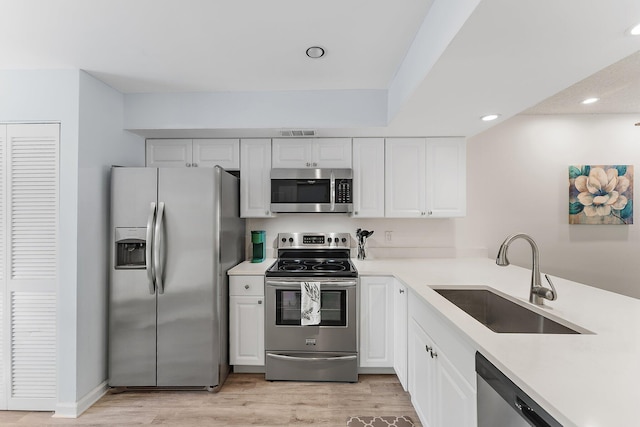 kitchen featuring stainless steel appliances, white cabinetry, light hardwood / wood-style floors, and sink