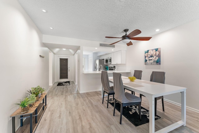 dining space with light hardwood / wood-style floors, a textured ceiling, and ceiling fan