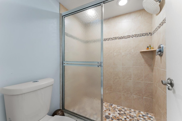 bathroom with a shower with door and toilet