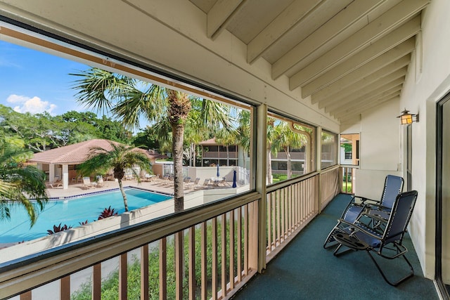 sunroom / solarium featuring vaulted ceiling with beams