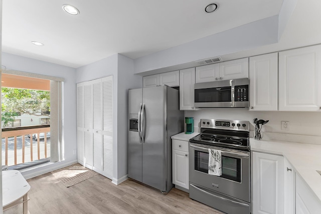 kitchen with white cabinets, appliances with stainless steel finishes, and light hardwood / wood-style flooring