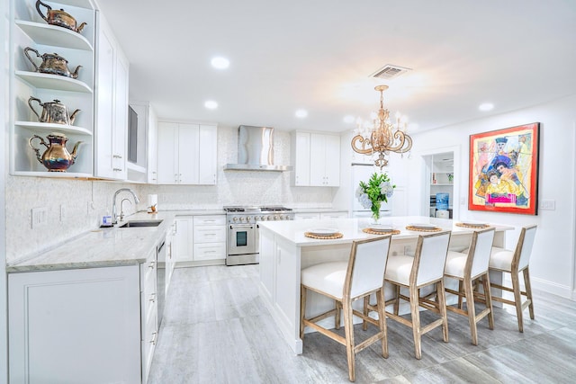 kitchen with sink, white cabinets, a center island, wall chimney exhaust hood, and double oven range