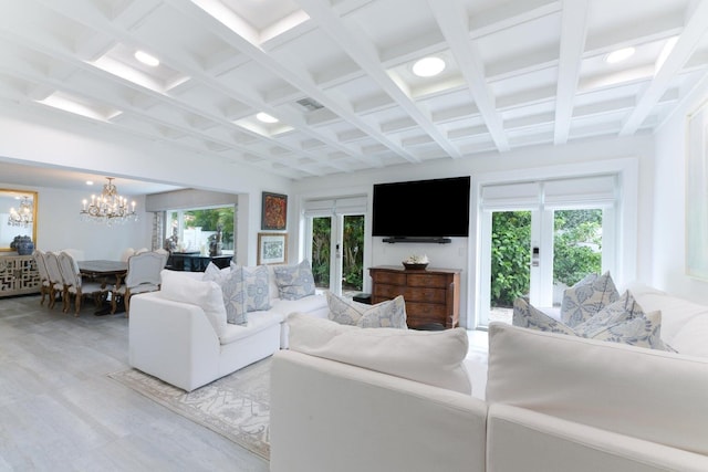 living room featuring coffered ceiling, a chandelier, light hardwood / wood-style floors, french doors, and beam ceiling