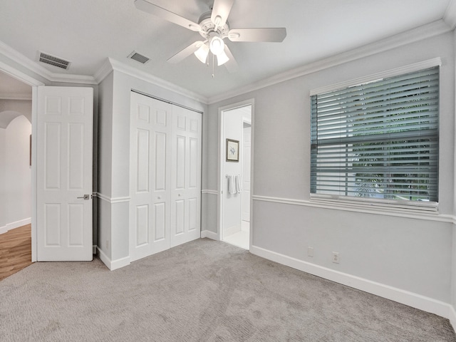 unfurnished bedroom featuring ornamental molding, light carpet, ceiling fan, and a closet