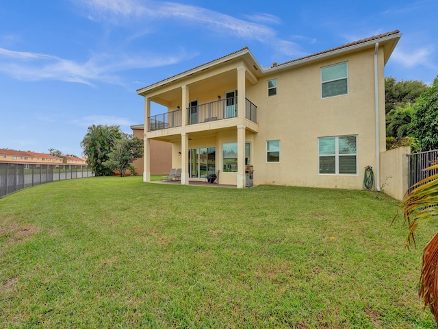 back of house featuring a patio, a balcony, and a lawn