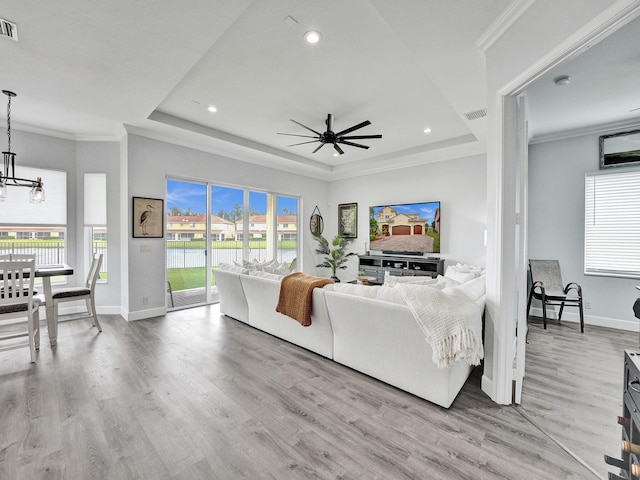 living room featuring a healthy amount of sunlight, ceiling fan with notable chandelier, and light hardwood / wood-style flooring