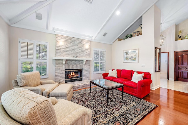 living room with high vaulted ceiling, hardwood / wood-style flooring, and a brick fireplace