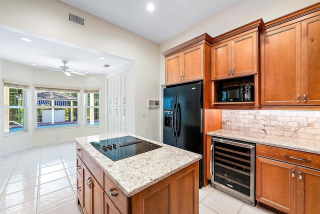 kitchen with light tile patterned floors, light stone countertops, black appliances, decorative backsplash, and beverage cooler