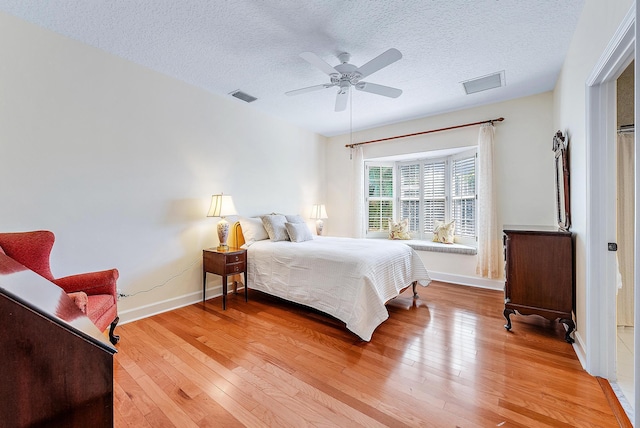 bedroom with ceiling fan, a textured ceiling, and hardwood / wood-style flooring