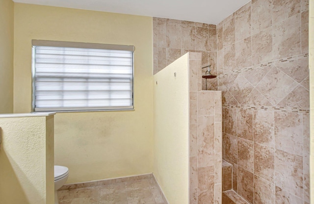 bathroom featuring toilet and a tile shower