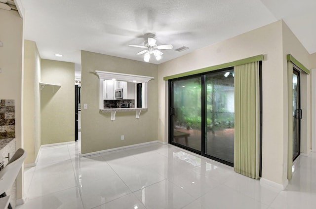 tiled empty room featuring ceiling fan and a textured ceiling